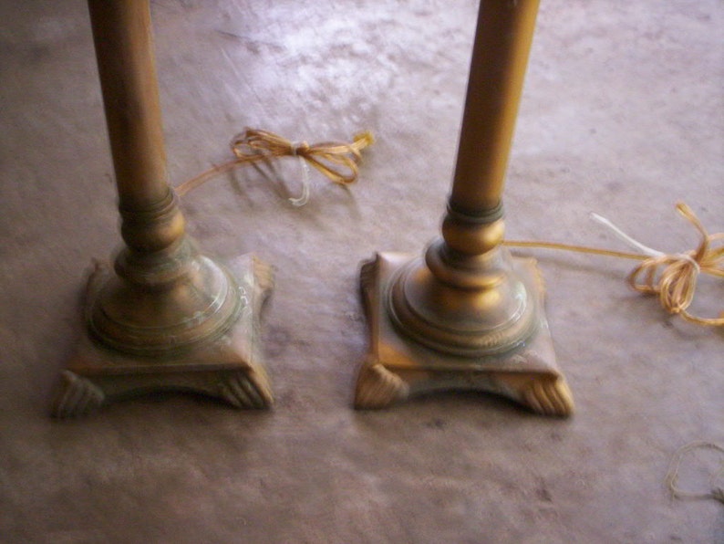 May include: Two gold-toned metal table lamps with ornate bases. The lamps have a vintage style and are in good condition.