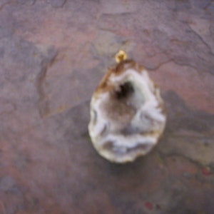 May include: A white and brown agate geode pendant with a gold-colored bail.
