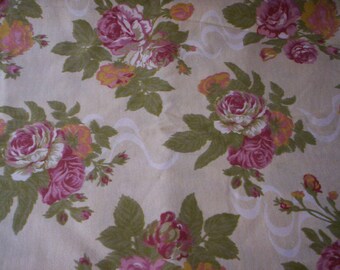 May include: A cream-colored fabric with a repeating pattern of pink and white roses. The roses are surrounded by green leaves.