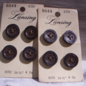 Può includere: Due carte di bottoni in plastica marrone con il testo "Lansing" e "8644 60¢" stampato su di esse. I bottoni sono disposti in una griglia sulle carte. Le carte hanno anche il testo "Dimensione 24-1/2" stampato su di esse.