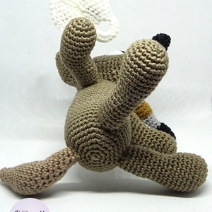 Puede incluir: Un juguete de perro de crochet marr&oacute;n que sostiene una taza de crochet blanca. El perro est&aacute; sentado sobre una superficie blanca.