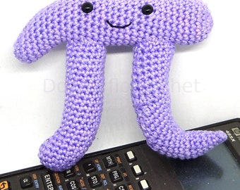 May include: A purple crocheted plush toy shaped like the mathematical symbol pi. The toy has a smiling face with two black eyes.