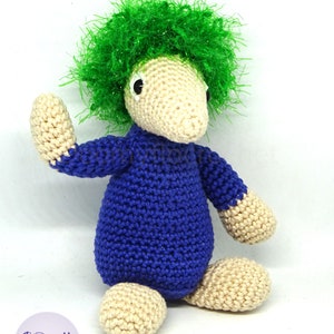 May include: A crocheted plush toy with a blue body, beige legs and arms, and a green fluffy hairdo.