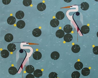May include: A teal fabric featuring a repeating pattern of stylized herons and lily pads. The herons are depicted in white, gray, and red, with orange beaks and legs. The lily pads are dark green with yellow accents.