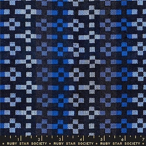May include: Close-up of a fabric with a geometric pattern in shades of blue and white on a dark background. The design features a repeating cross-like motif. The bottom of the image includes a ruler and the text "RUBY STAR SOCIETY".