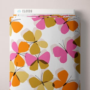 May include: A roll of fabric with a repeating butterfly pattern in orange, pink, and gold on a white background. The butterflies have black antennae and are arranged in a scattered design. The text "CLOUD9" is visible on the top edge.