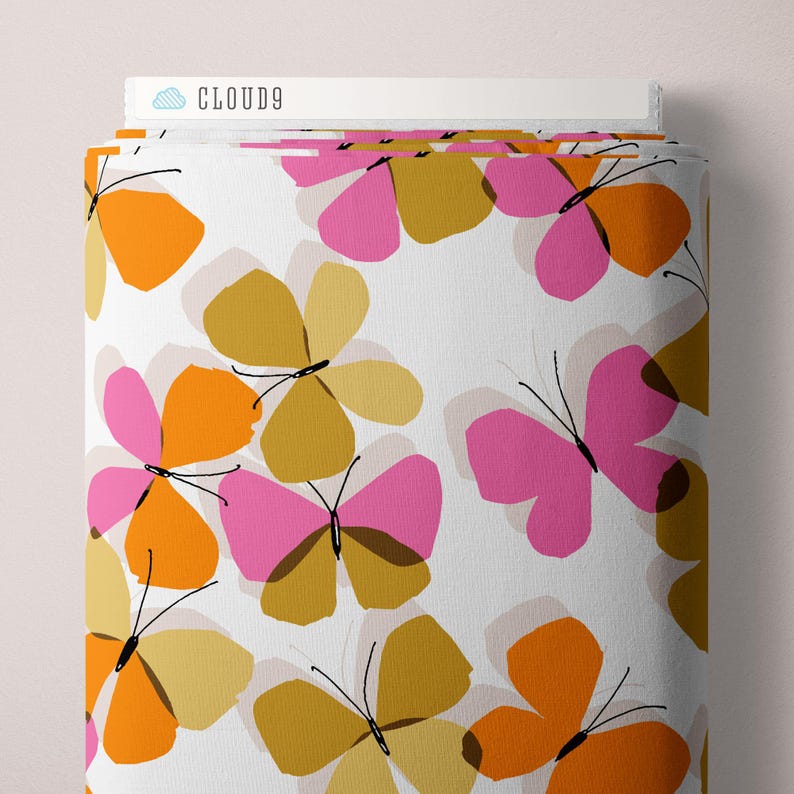 May include: A roll of fabric with a repeating butterfly pattern in orange, pink, and gold on a white background. The butterflies have black antennae and are arranged in a scattered design. The text "CLOUD9" is visible on the top edge.