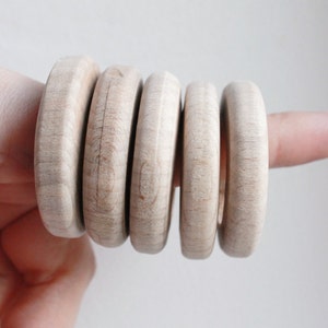 May include: A set of five wooden rings, stacked on top of each other. The rings are all the same size and shape, and they are made of a light-coloured wood.