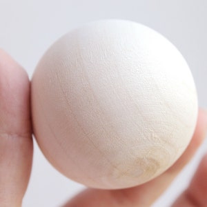 May include: A white, smooth, round egg held in a hand.