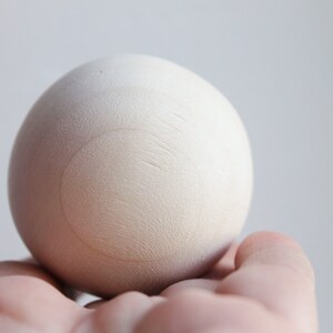 May include: A white wooden egg with a circle drawn on it.