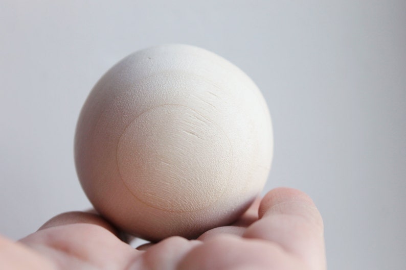 May include: A white wooden egg with a circle drawn on it.