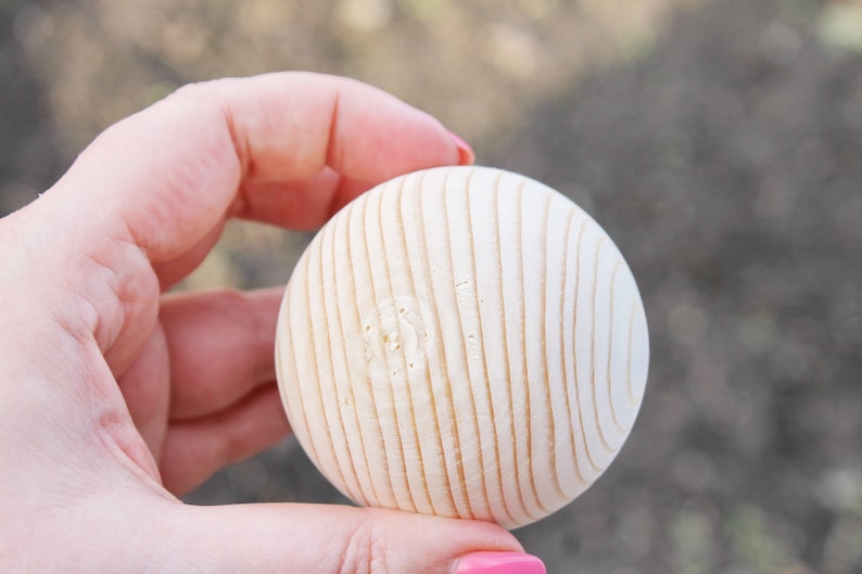 Puede incluir: Una bola de madera lisa y blanca con textura acanalada. La bola tiene un di&aacute;metro de aproximadamente 5 cm.