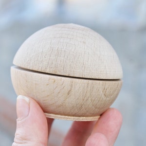May include: A wooden box with a round lid, made of light wood with a natural finish. The box is open and the lid is resting on top of the box.