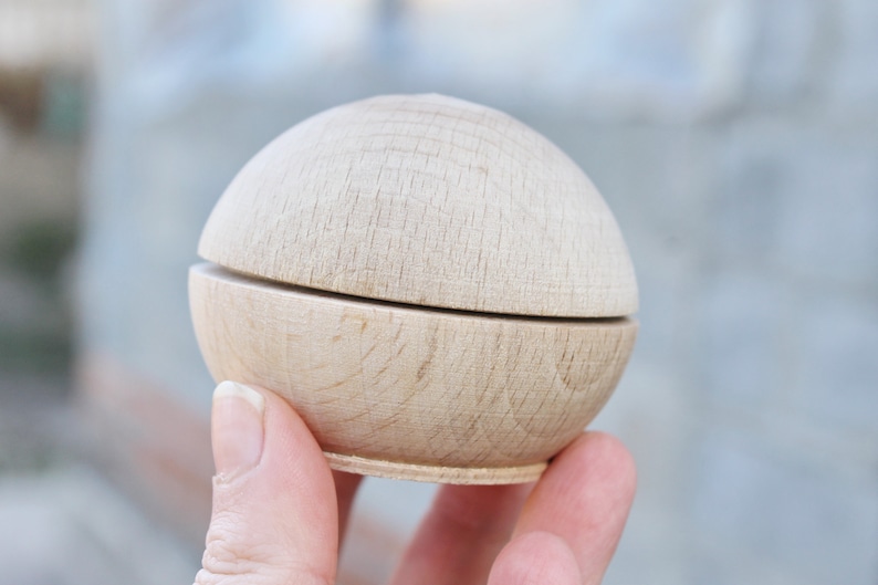 May include: A wooden box with a round lid, made of light wood with a natural finish. The box is open and the lid is resting on top of the box.