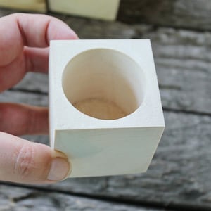 Può includere: Un vaso di legno bianco con un'apertura rotonda. Il vaso è in legno grezzo e ha una venatura del legno naturale.