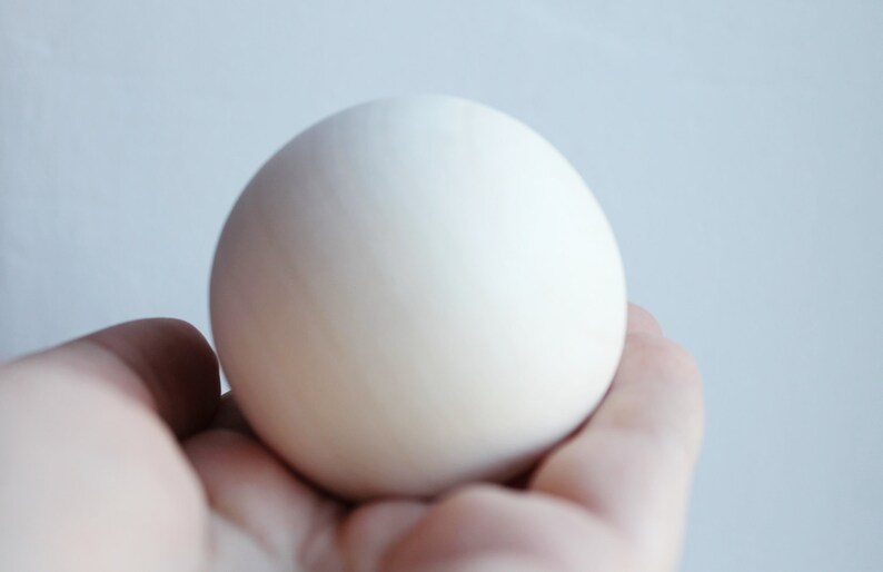 May include: A white egg held in a hand.