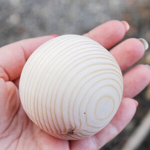 Puede incluir: Una bola de madera blanca con un patr&oacute;n de c&iacute;rculos conc&eacute;ntricos. La bola est&aacute; siendo sostenida en la mano de una persona.