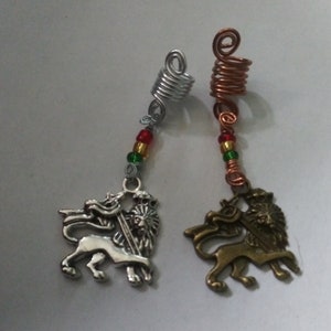 Peut inclure: Deux spirales pour cheveux avec des breloques en forme de tête de lion. Les spirales sont en fil d'argent et de cuivre et sont décorées de perles rouges, vertes et jaunes. Les breloques en forme de tête de lion sont en argent et en bronze.