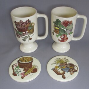 May include: Two cream-colored pedestal mugs and two matching coasters. The mugs feature illustrations of food items like olives, shrimp, and vegetables. The coasters have similar food-themed designs, including bread, cheese, and fruit. A charming kitchenware set.