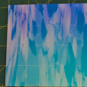 May include: A close-up of a blue and purple iridescent background with a white grid pattern. The grid pattern has numbers printed on it.