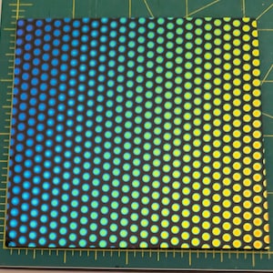 May include: A sheet of iridescent holographic vinyl with a repeating pattern of small circles. The circles transition from blue to yellow.