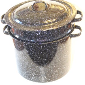 May include: A black enamel stockpot with a white speckled pattern, featuring two side handles and a matching lid with a central handle. The cylindrical pot has a wide rim and a deep basin, constructed with a durable finish and a classic design.