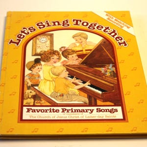 May include: A vintage children's book titled "Let's Sing Together" with a yellow cover. The cover features an illustration of children and adults around a piano. The book is labeled "Favorite Primary Songs" and includes the text "With Matching Recording".