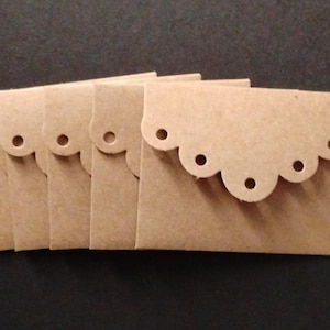 May include: A set of five small, light brown rectangular envelopes made of cardstock. Each envelope features a decorative scalloped flap with a series of circular cutouts along the edge, creating a distinct, uniform pattern across all five items.