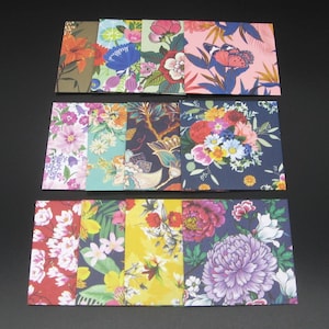 May include: A collection of eleven rectangular paper envelopes featuring diverse floral and botanical patterns. The designs include various color palettes such as pink, yellow, navy blue, and green, showcasing illustrations of lilies, peonies, and butterflies.