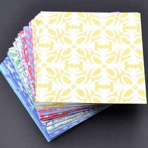 May include: A stack of colorful patterned paper squares. The top square is yellow with a white floral design.
