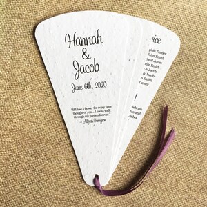 May include: A white paper fan with a purple ribbon. The fan has the names Hannah & Jacob and the date June 6th, 2020 printed on it. The fan also has a quote by Alfred Tennyson: "If I had a flower for every time thought of you... I could walk through my garden forever."