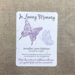 May include: A white card with purple butterfly illustrations and the text "In Loving Memory" and "Jennifer Lynn Davison 3.8.1967-8.12.2027". The card also includes the text "What the caterpillar perceives as the end, to the butterfly is just the beginning. Plant this card and wildflowers will grow as a symbol of life and love remembered."