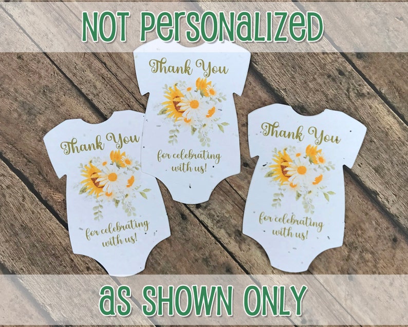 K&ouml;nnte beinhalten: Drei wei&szlig;e Baby-Strampler-f&ouml;rmige Dankeskarten mit einem Sonnenblumen- und G&auml;nsebl&uuml;mchen-Blumendesign. Der Text auf den Karten lautet "Vielen Dank f&uuml;rs Feiern mit uns!"