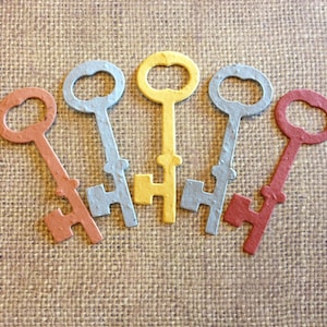 May include: Five decorative keys made of paper, each in a different color: gray, yellow, red, brown, and blue. The keys are arranged in a semi-circle, with the yellow key at the top.