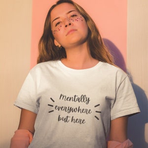 May include: White t-shirt with the text "mentally everywhere but here" printed on the front.