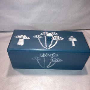 Vintage houten kist blauwe kist met gestencilde champignons en een knop van harspaddestoel
