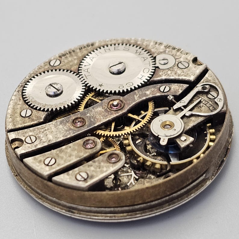 May include: Close-up of a vintage watch movement. The mechanism features multiple gears, screws, and the text "HAVANNES WATCH CO." and "SWISS MADE". The watch has 17 jewels and is encased in a circular metal frame.