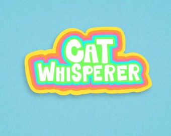 May include: A colorful sticker with the text "CAT WHISPERER" in white letters with a rainbow outline.