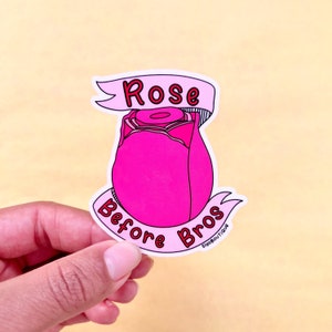 May include: A pink rose bud sticker with the text "Rose Before Bros" in red and white lettering.