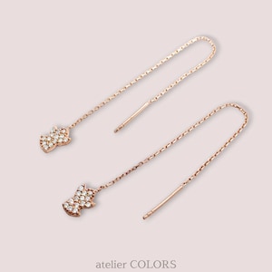 Puede incluir: Un par de pendientes de oro rosa con una cadena delicada y un peque&ntilde;o colgante en forma de diamante brillante.