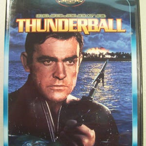 May include: DVD case for the James Bond film "Thunderball" featuring Sean Connery. The cover art shows Connery in water, holding a spear gun, with the film's title in large, yellow letters. The MGM logo is at the top.