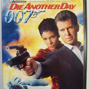 May include: DVD case for the movie "Die Another Day" featuring Pierce Brosnan and Halle Berry. The cover art shows the actors with guns, set against a backdrop of explosions and the 007 logo. The text "Die Another Day" is prominently displayed.