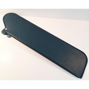 May include: A dark teal automotive sun visor with a smooth, rectangular shape and rounded edges. The visor features a sturdy mounting bracket on one side, designed for attachment to a vehicle interior, with a clean, solid-colored surface.
