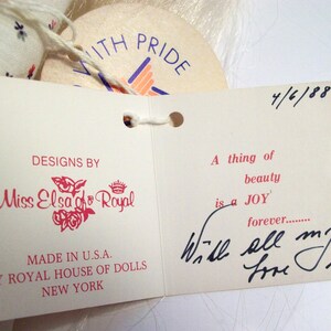 May include: A white tag with pink lettering that reads "Designs by Miss Elsa of Royal" and "Made in U.S.A. by Royal House of Dolls New York". A second white tag with black lettering reads "A thing of beauty is a JOY forever... Will all my love Elsa". The date "4/6/88" is written in black ink on the top right corner of the second tag.