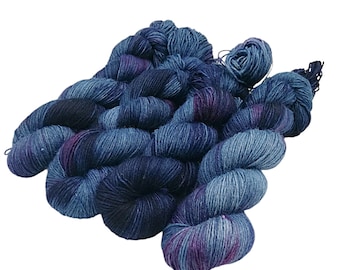 May include: A skein of blue, purple and black yarn with a variegated colour pattern. The yarn is soft and fluffy, and it is perfect for knitting or crocheting.