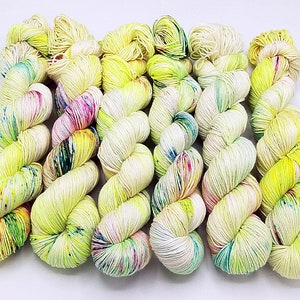 Peut inclure: Une pelote de laine jaune avec des mouchetures colorées. La laine est enroulée en forme de boule et est prête pour le tricot ou le crochet.