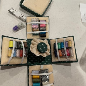 May include: A green Singer sewing kit with a variety of colored threads, needles, and a pincushion. The kit is open and the different compartments are visible.