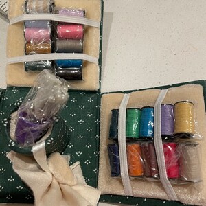 May include: A green fabric sewing kit with a variety of colored threads, a needle holder, and a small white fabric square. The kit is open and the threads are organized in rows.