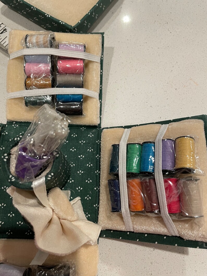 May include: A green fabric sewing kit with a variety of colored threads, a needle holder, and a small white fabric square. The kit is open and the threads are organized in rows.
