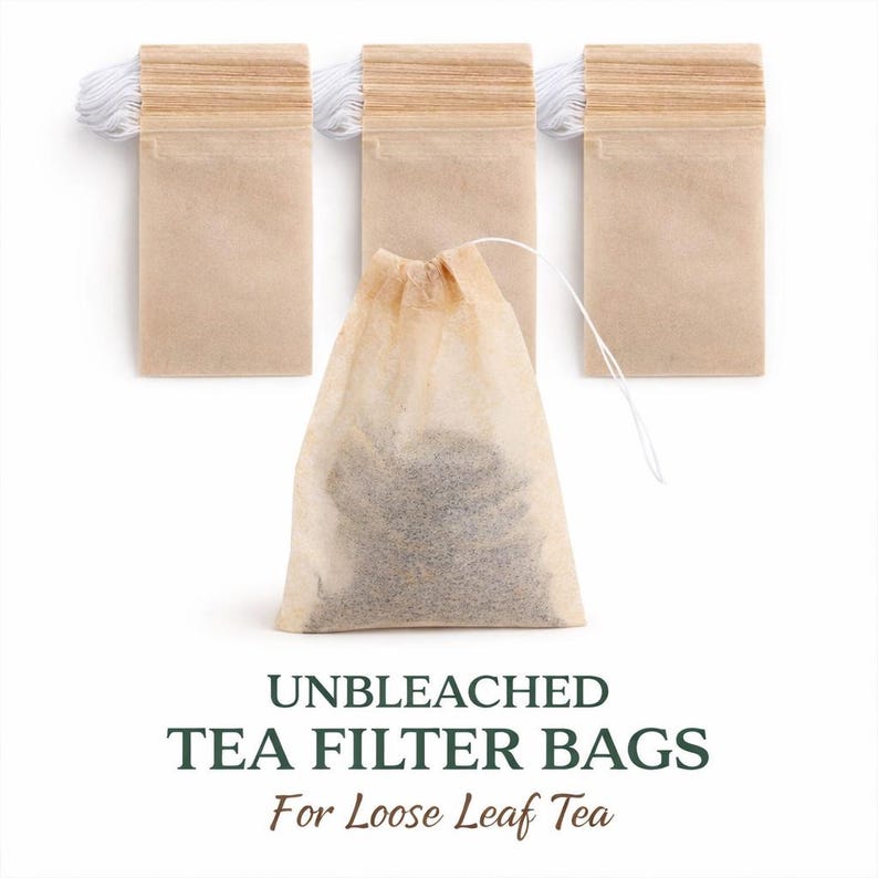 Unbleached drawstring tea filter bags for loose leaf tea, natural disposable paper tea infusers with one filled herbal tea bag on white background